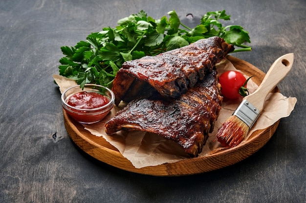 Grilled and smoked pork ribs with barbeque sauce on an old vintage wooden cutting board. Tasty snack to beer. Closeup image.