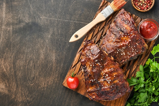 Grilled and smoked pork ribs with barbeque sauce on an old vintage wooden cutting board. Tasty snack to beer. Closeup image.