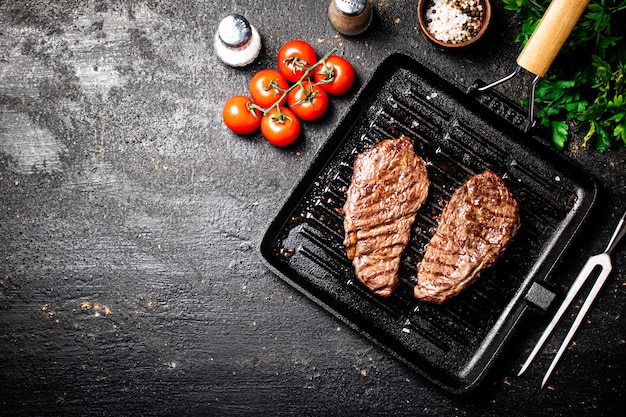 Photo grilled steak in a frying pan with tomatoes and spices