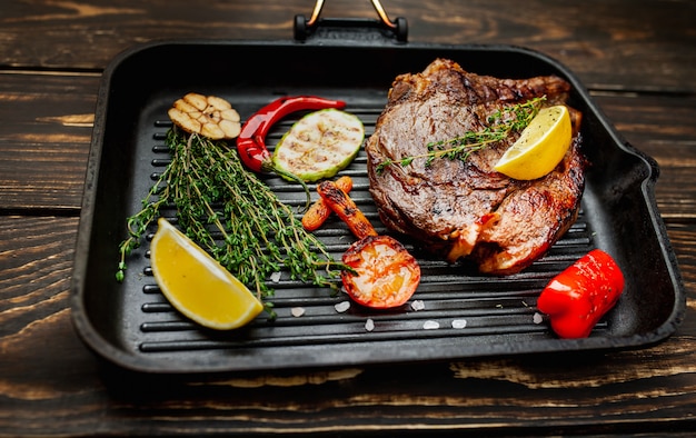 grilled steak in a pan with spices and grilled vegetables on wood! delicious dinner