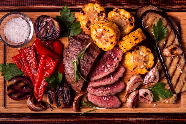 Foto bistecca alla griglia e verdure sul tagliere.