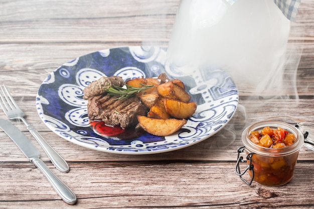 Grilled steak with baked golden potatoes on a wooden