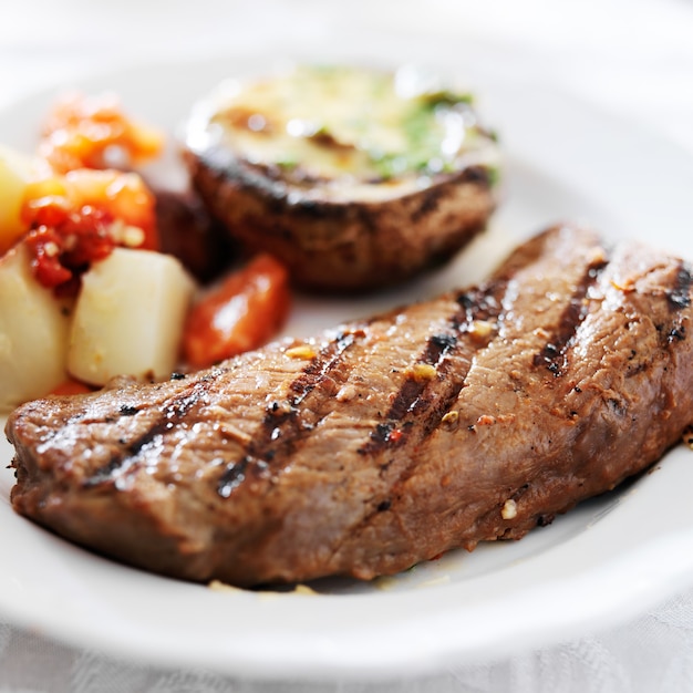 Foto bistecca alla griglia con patate e funghi ripieni