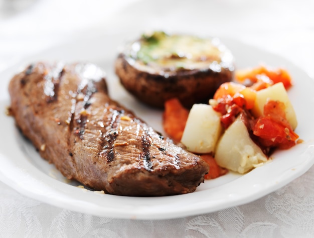 Foto bistecca alla griglia con patate e funghi ripieni