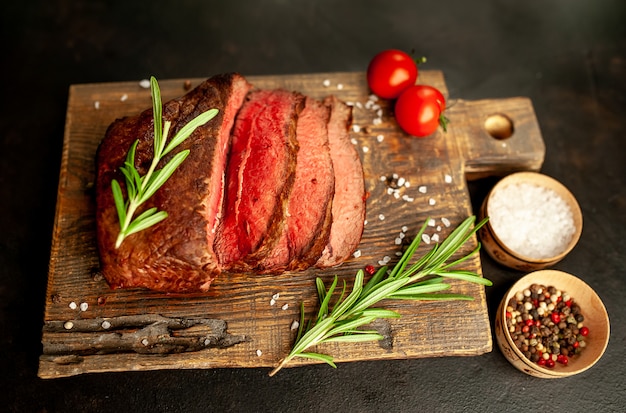 grilled steak with spices on a cutting board, stone background, top view