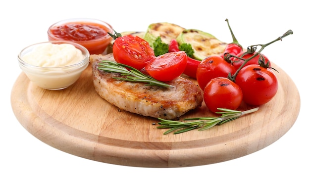 Grilled steak with spices herbs and vegetables on wooden board isolated on white