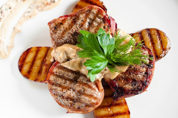 Grilled steaks and potatoes on white plate