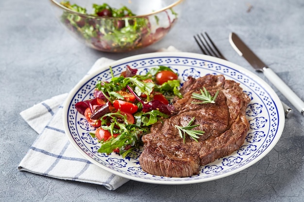 Grilled steaks and vegetable salad on light background table setting food concept