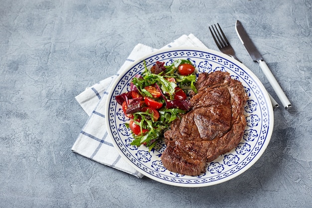 Grilled steaks and vegetable salad. Table setting, food concept.