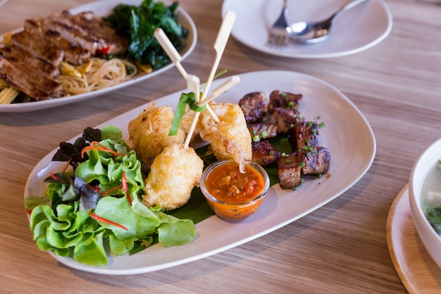 Grilled sticky rice with egg served with grilled diced steak with salad.