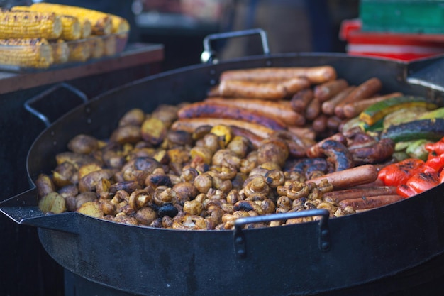 Grilled street food meat with vegetables on a large grill pan are mushrooms potatoes peppers