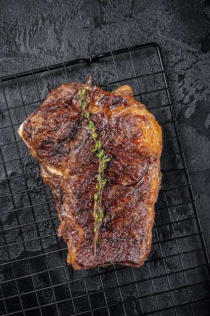 Grilled Striploin beef meat steak or new york steak on a grill rack Black background Top view