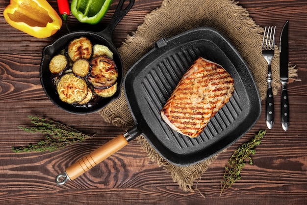 Photo grilled striploin on grill pan and fried eggplant on wooden background
