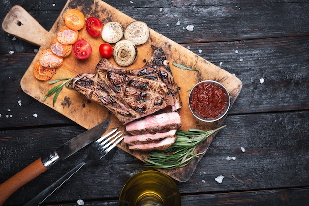 구운 된 striploin 돌 테이블 위에 절단 보드에 스테이크를 슬라이스. 복사 공간이있는 평면도