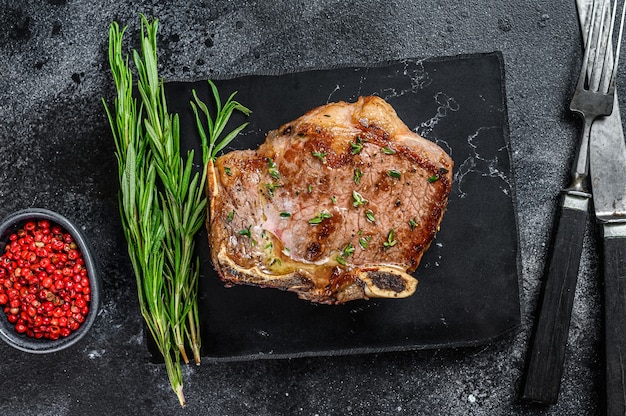 Photo grilled striploin steak on the bone or new york steak. black background. top view.