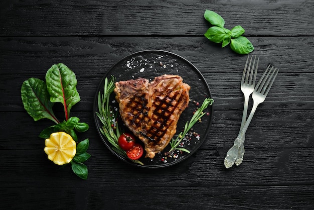 Photo grilled tbone steak with rosemary and spices on an old background top view free copy space