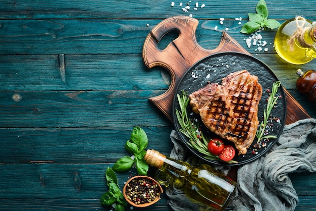 Grilled Tbone steak with rosemary and spices On an old background Top view Free copy space