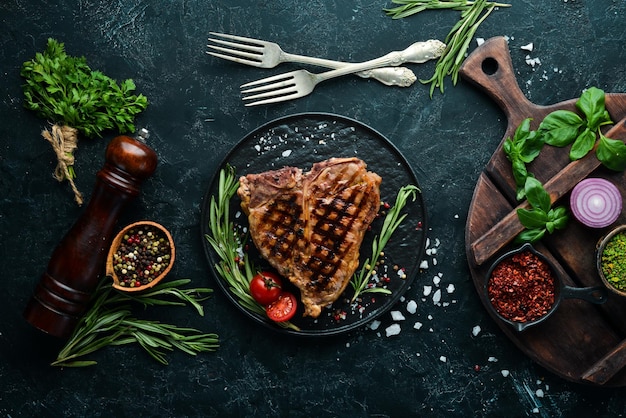 Grilled Tbone steak with rosemary and spices On an old background Top view Free copy space