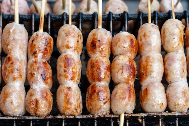 Grilled Thai sausage at street food market in Thailand, close up. Traditional Thai sausage with pork and rice, delicious street food.