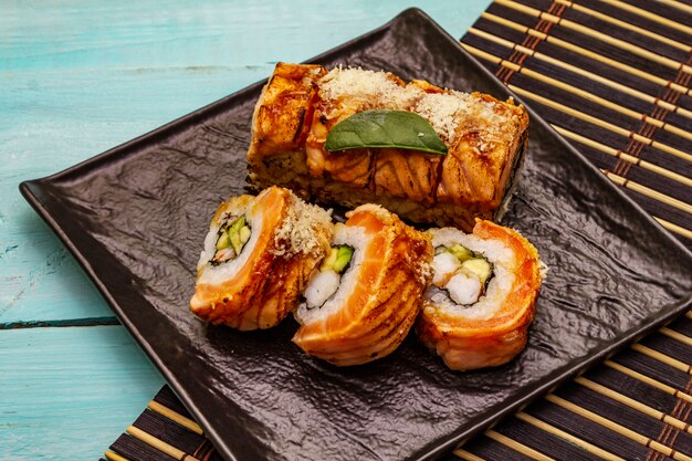 Grilled tiger prawn sushi. Japanese or Korean roll with different fresh ingredients. Trendy turquoise background