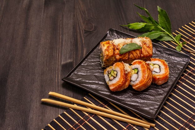 Фото Жареные суши с тигровыми креветками. японский или корейский ролл с различными свежими ингредиентами. модный черный фон