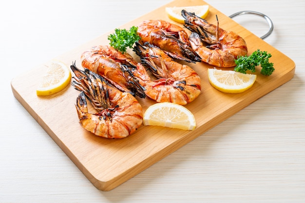 grilled tiger prawns or shrimps with lemon on wood board