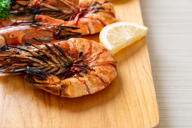 grilled tiger prawns or shrimps with lemon on wood board