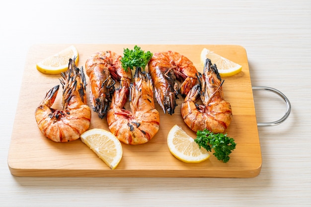 grilled tiger prawns or shrimps with lemon on wood board