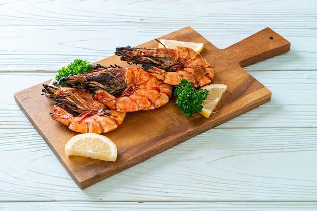 grilled tiger prawns or shrimps with lemon on wood board