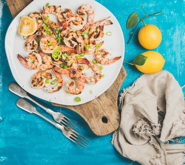 Photo grilled tiger prawns in white plate with lemon leek chili