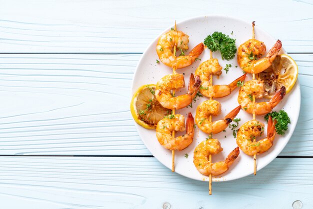 Grilled tiger shrimps skewers with lemon