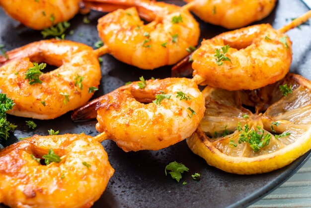 Grilled tiger shrimps skewers with lemon