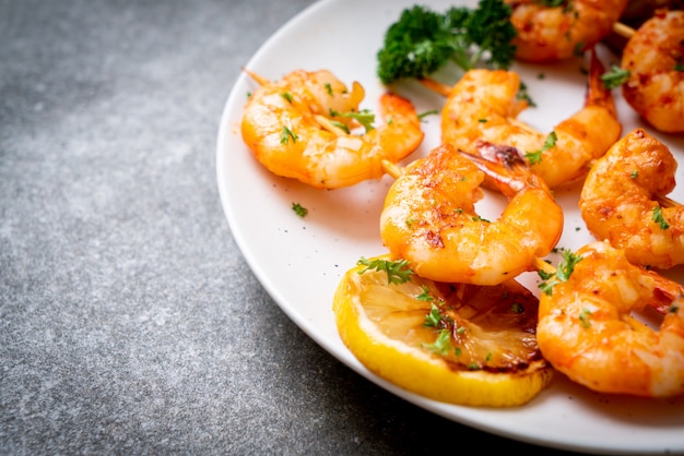 Grilled tiger shrimps skewers with lemon