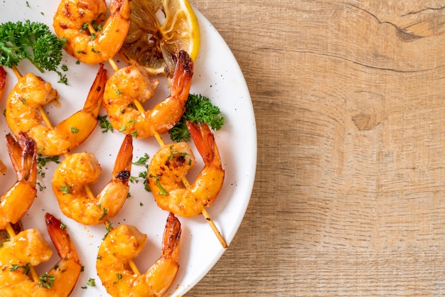 Grilled tiger shrimps skewers with lemon