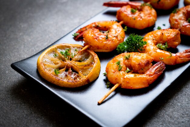 Grilled tiger shrimps skewers with lemon