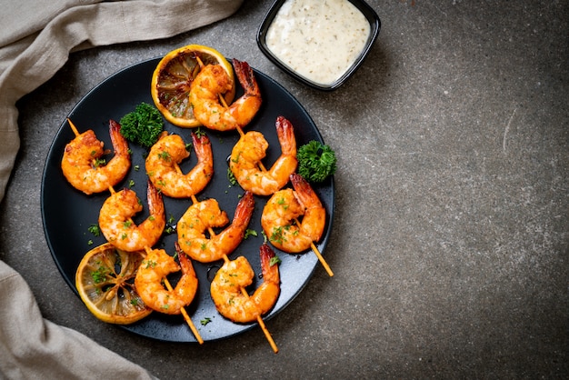 Grilled tiger shrimps skewers with lemon