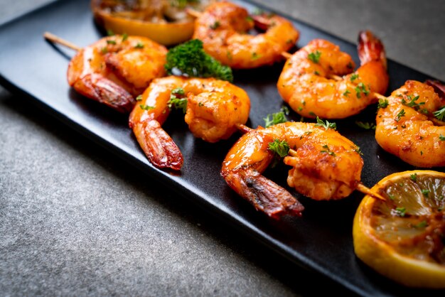 Grilled tiger shrimps skewers with lemon