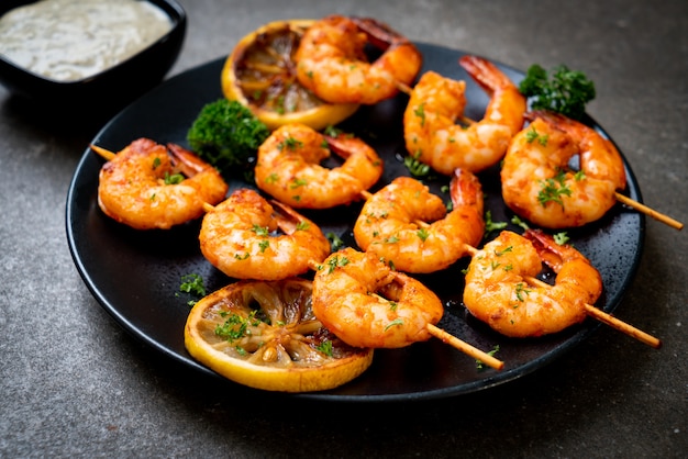 Grilled tiger shrimps skewers with lemon