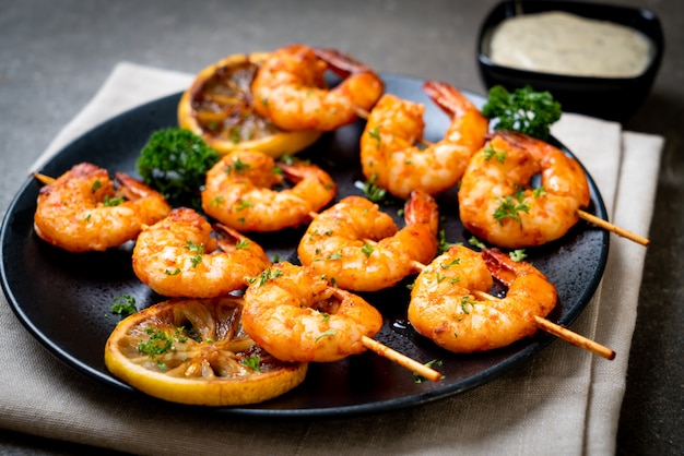 Grilled tiger shrimps skewers with lemon