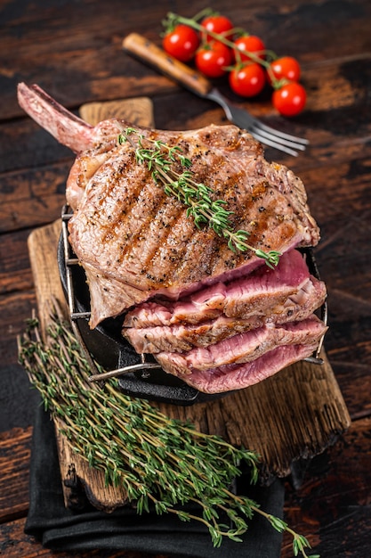 Grilled Tomahawk rib eye steak on grill with herbs Wooden background Top view