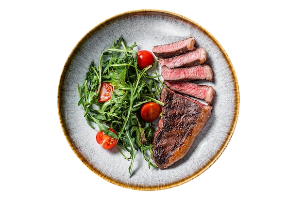 野菜サラダと白い背景に分離されたプレートのトップシロイン牛肉ステーキ