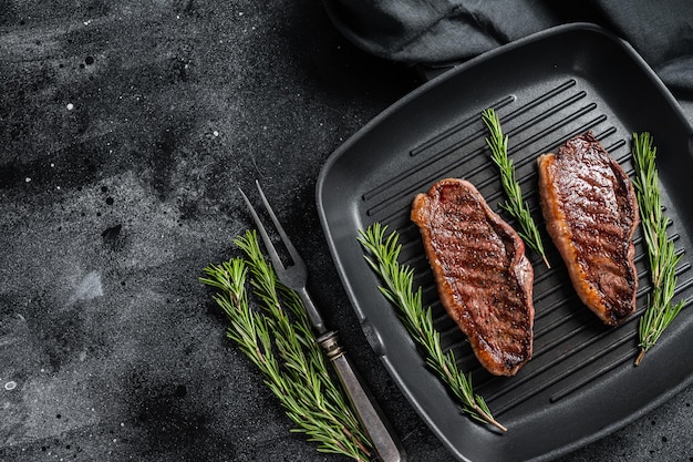 Grilled Top sirloin beef steak or brazilian Picanha roasted meat on grill pan Black background Top view Copy space