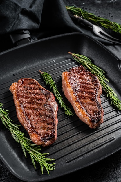 Grilled Top sirloin beef steak or brazilian Picanha, roasted meat on grill pan. Black background. Top view.