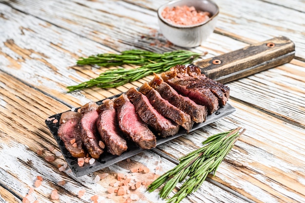 Grilled top sirloin cap or picanha steak on a meat cleaver with herbs