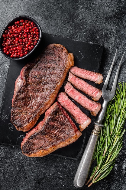 Grilled top sirloin or cup rump beef meat steak on marble board Black background Top view