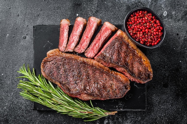 Photo grilled top sirloin or cup rump beef meat steak on marble board black background top view