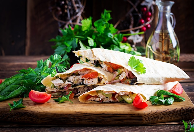 グリルしたトルティーヤは、木の板に鶏肉と新鮮な野菜を包みます。チキンブリトー。メキシコ料理。健康食品のコンセプト。メキシコ料理