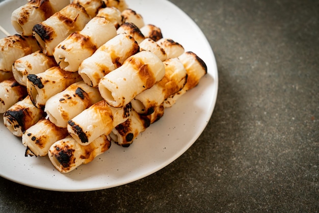 Grilled tube shaped fish paste cake or tube squid skewer on\
plate