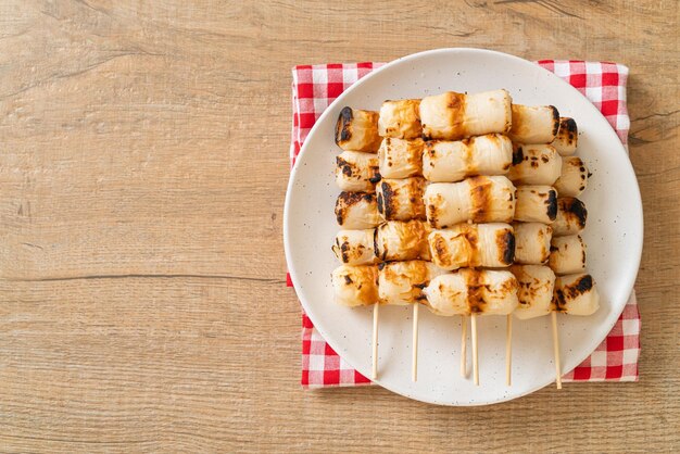 Grilled tube shaped fish paste cake or tube squid skewer on\
plate