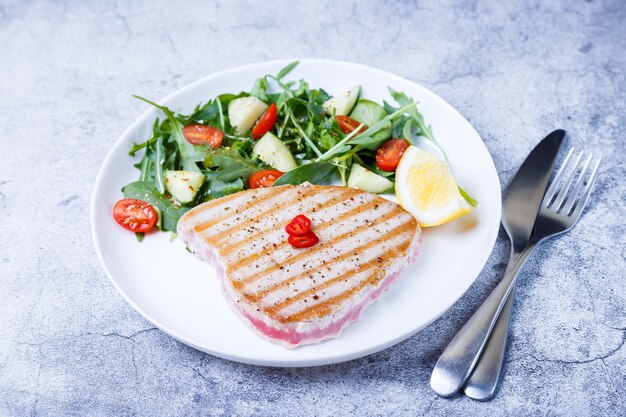 Tagliata di tonno alla griglia con verdure fresche, rucola, spinaci e limone. avvicinamento.